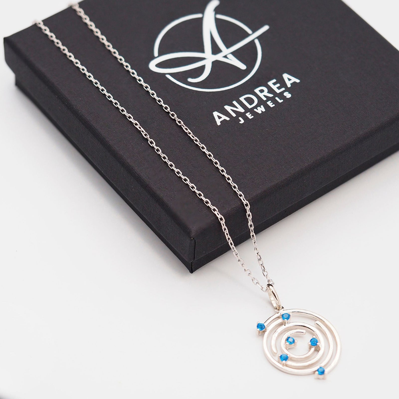 Collar Spiral de plata con piedra azul junto a su caja de regalo cerrada - Andrea Jewels