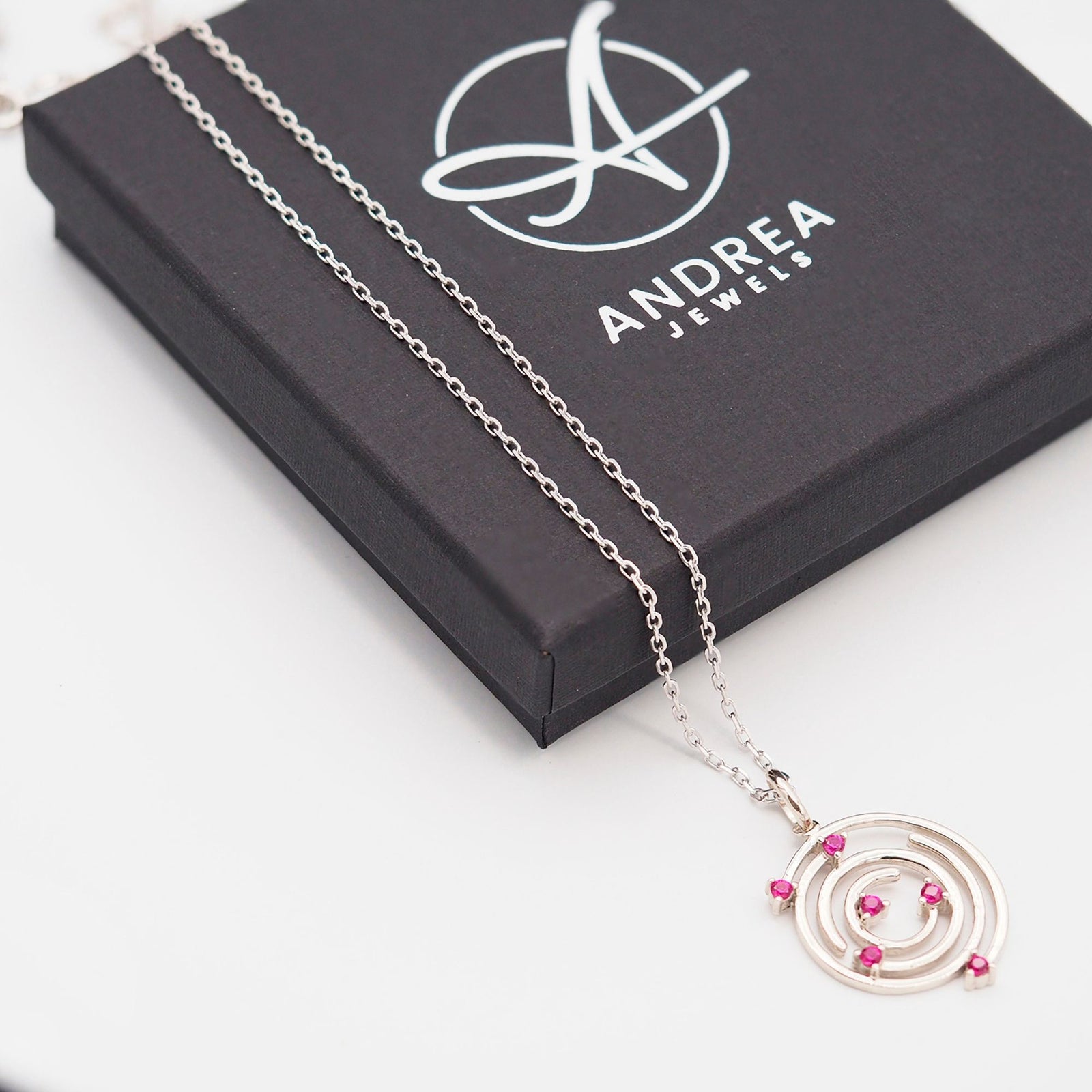 Collar Spiral de plata con piedra roja junto a su caja de regalo cerrada - Andrea Jewels