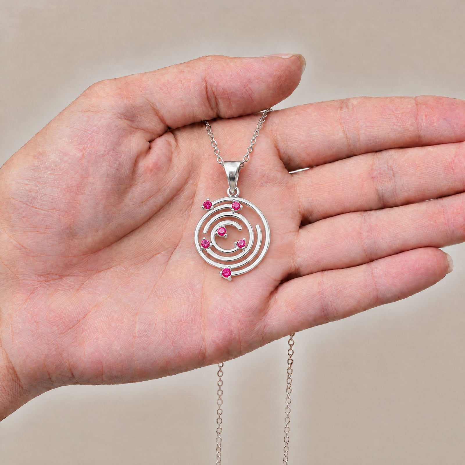 Collar Spiral de plata con piedra roja sobre una mano - Andrea Jewels
