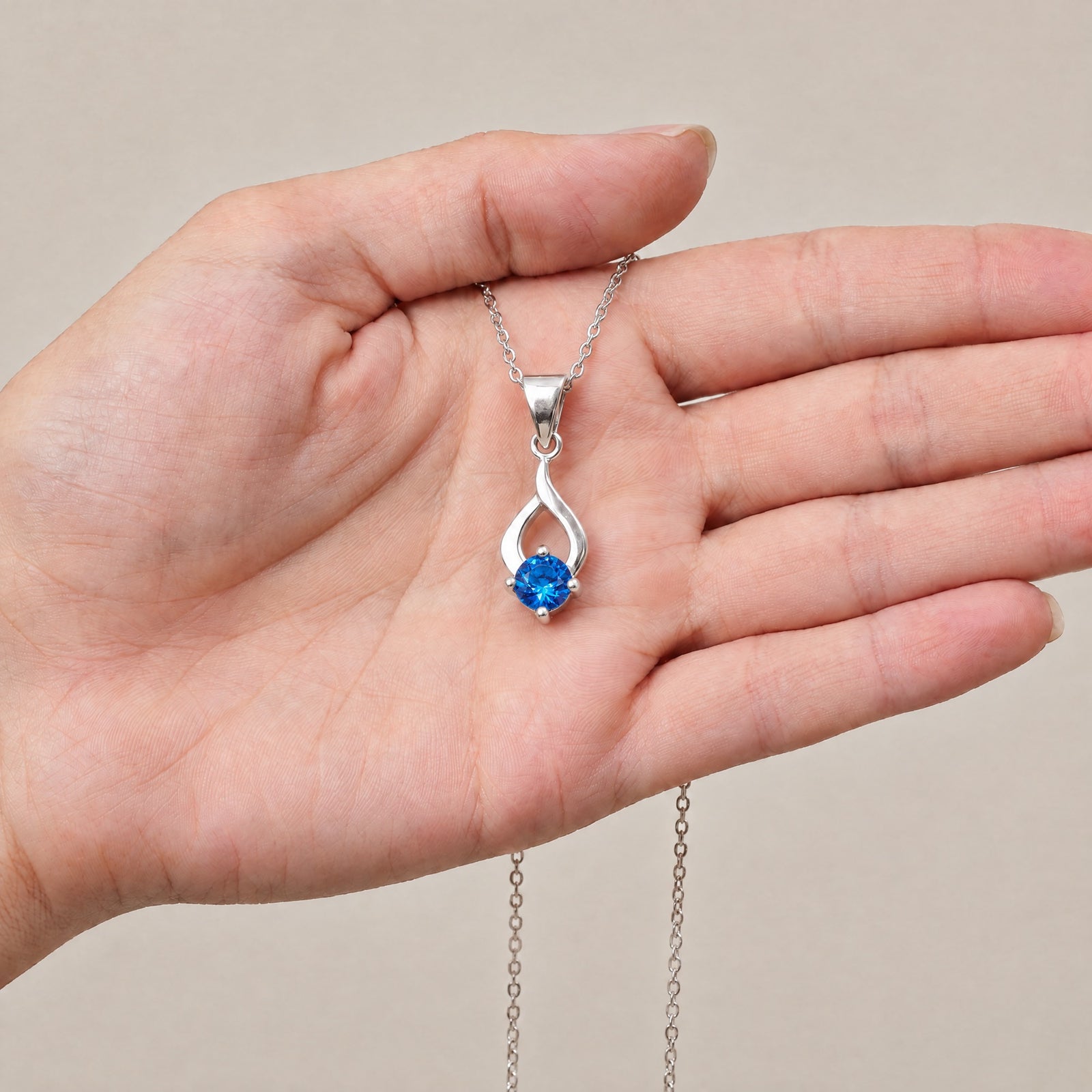 Collar Tear de plata con piedra azul sobre una mano - Andrea Jewels