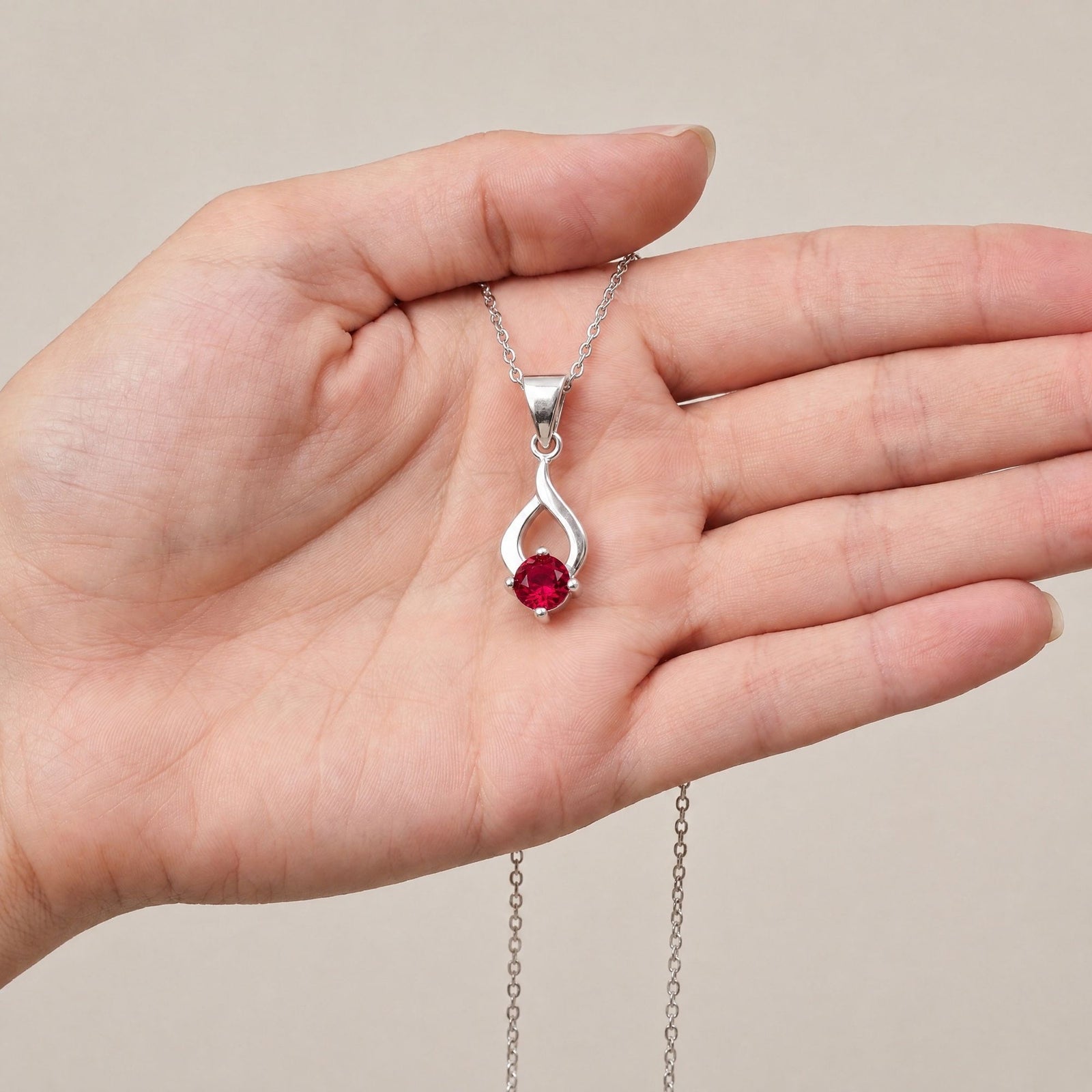 Collar Tear de plata con piedra roja sobre una mano - Andrea Jewels