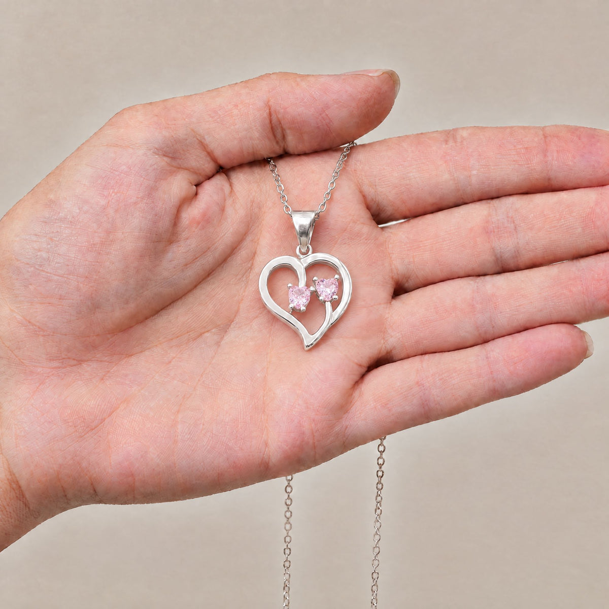 Collar Duo de plata con dos piedras rosas sobre una mano - Andrea Jewels