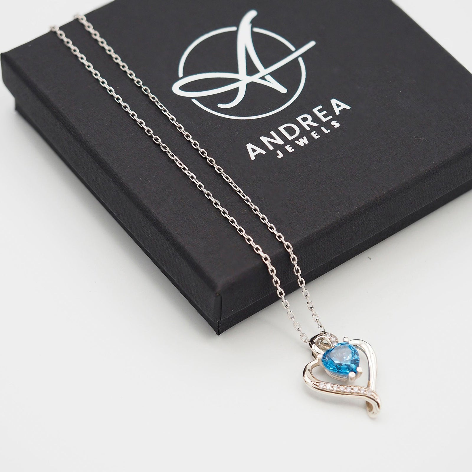 Collar Nina de plata con piedra azul topacio junto a su caja de regalo cerrada - Andrea Jewels