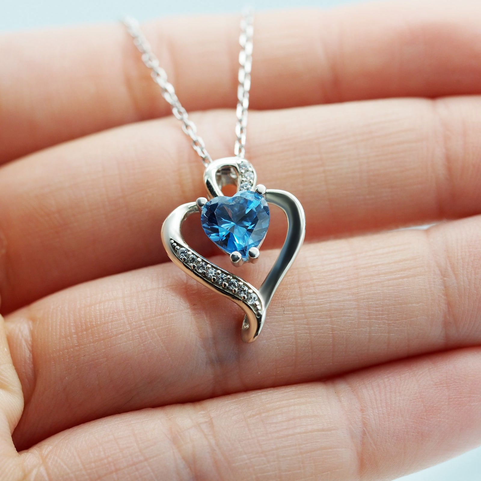 Collar Nina de plata con piedra azul topacio sobre una mano - Andrea Jewels