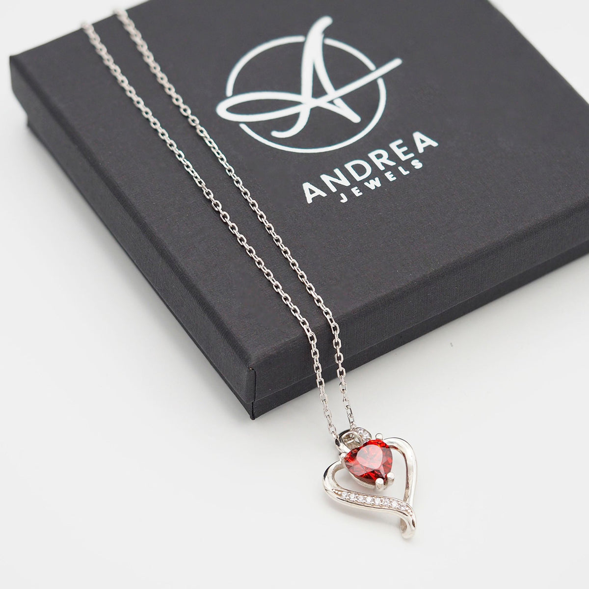 Collar Nina de plata con piedra naranja junto a su caja de regalo cerrada - Andrea Jewels