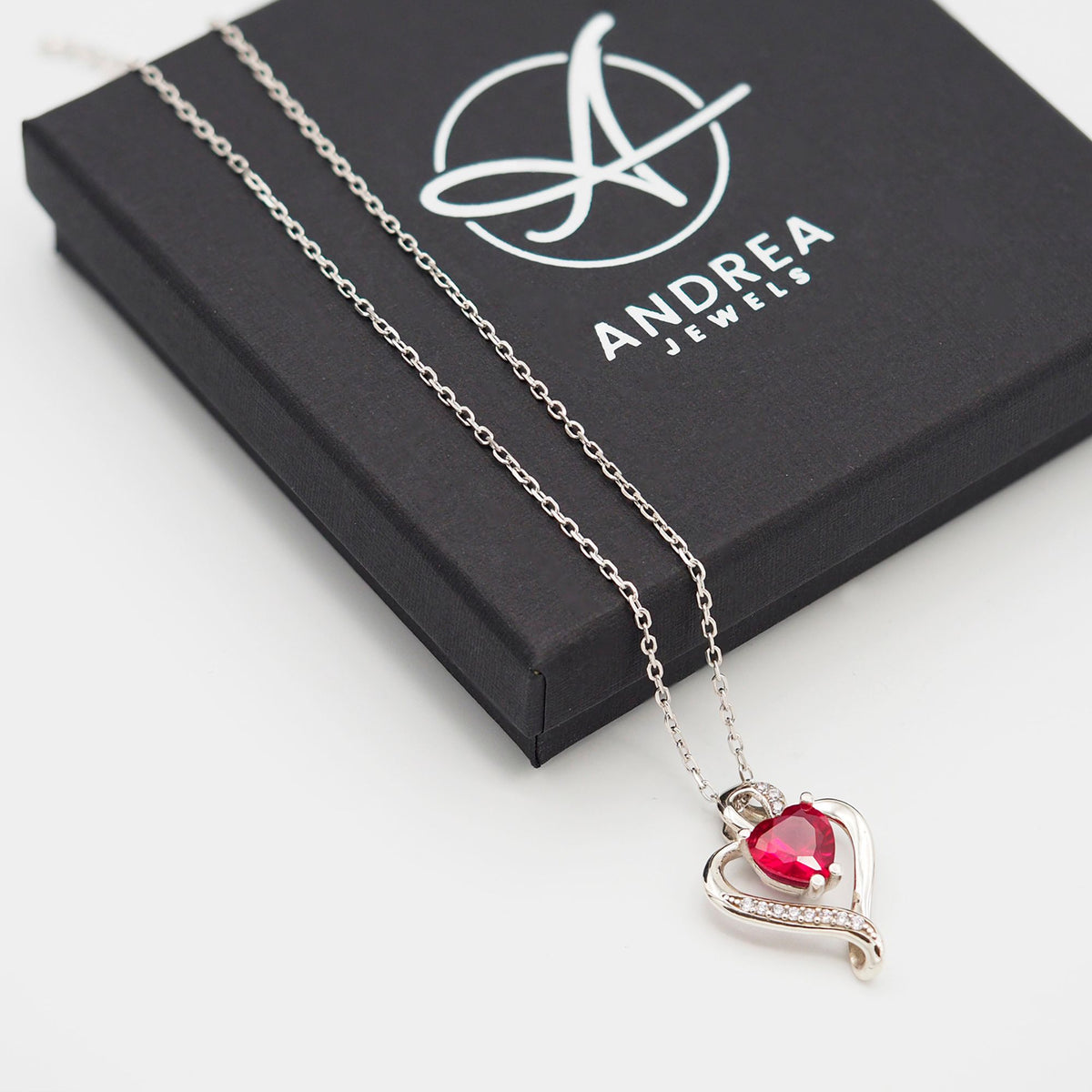 Collar Nina de plata con piedra roja junto a su caja de regalo cerrada - Andrea Jewels