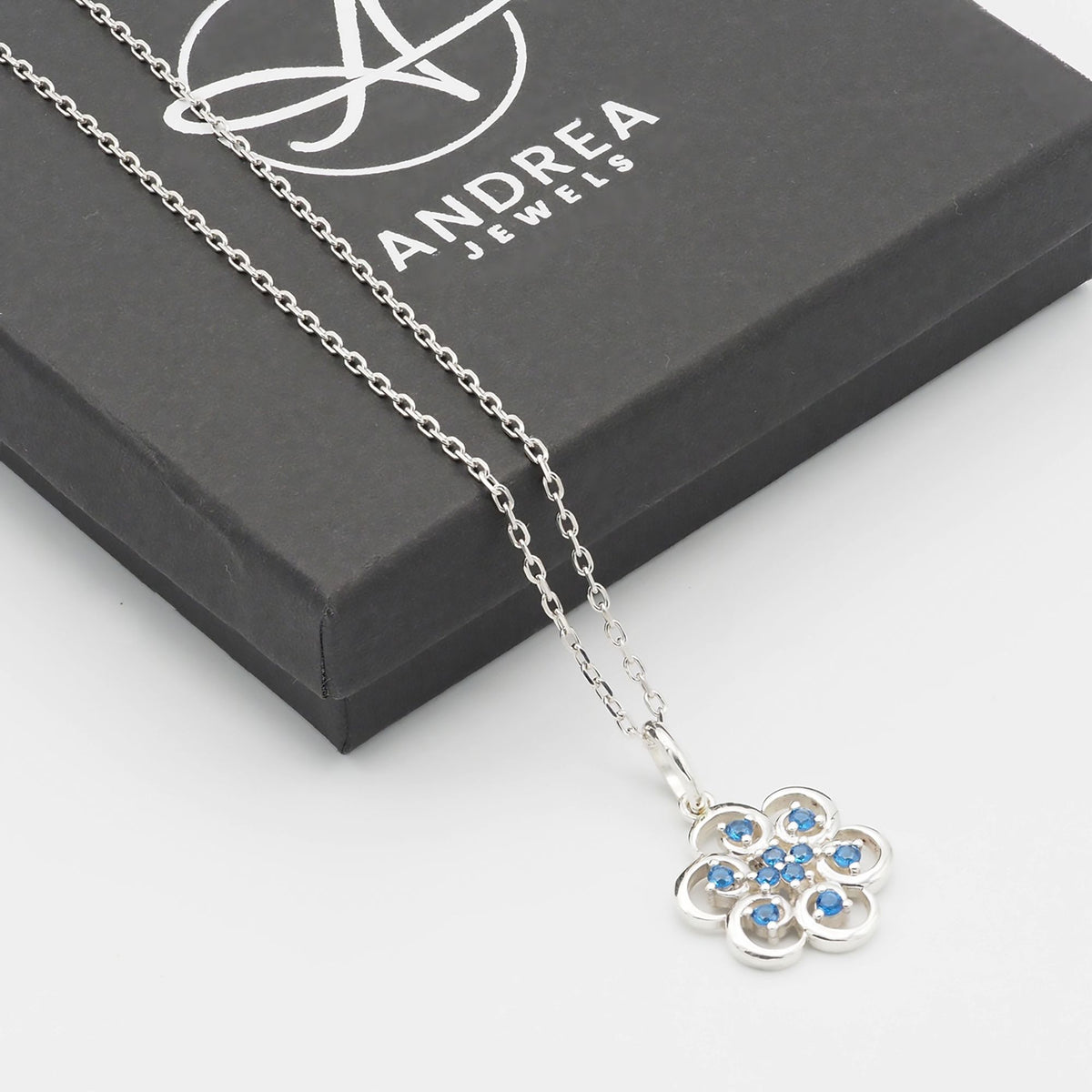 Collar Poppy de plata 925 con piedras azules junto a su caja de regalo cerrada - Andrea Jewels