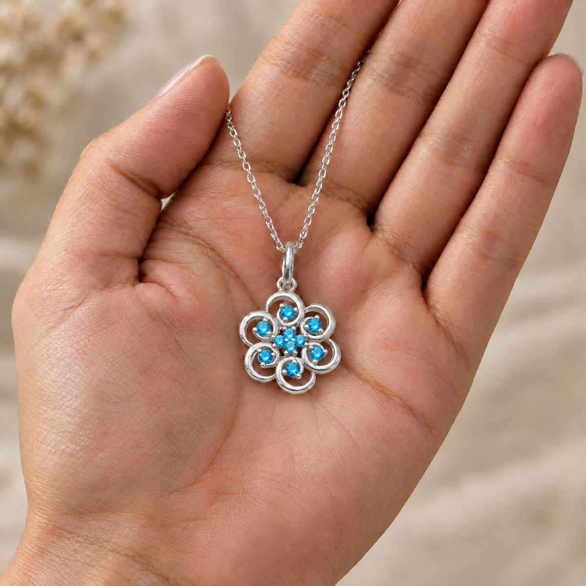 Collar Poppy de plata 925 con piedras azules sobre una mano - Andrea Jewels