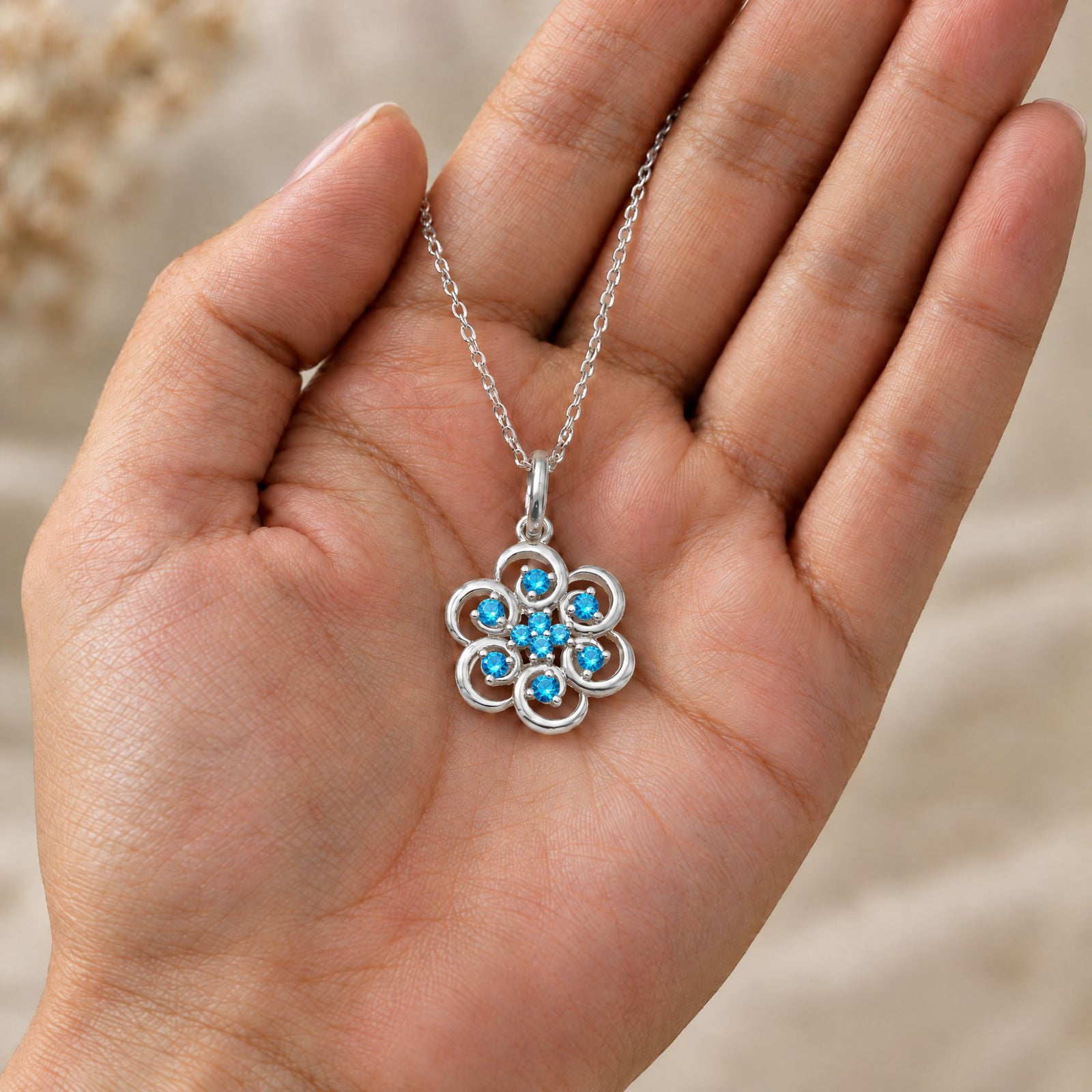 Collar Poppy de plata 925 con piedras azules sobre una mano - Andrea Jewels
