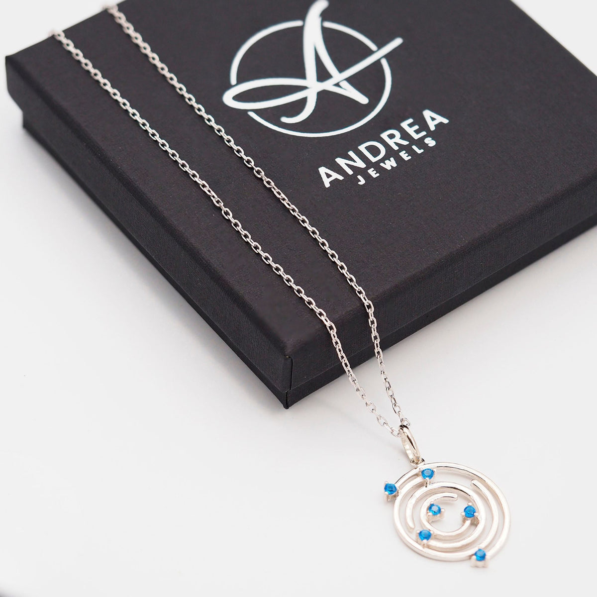 Collar Spiral de plata con piedra azul junto a su caja de regalo cerrada - Andrea Jewels