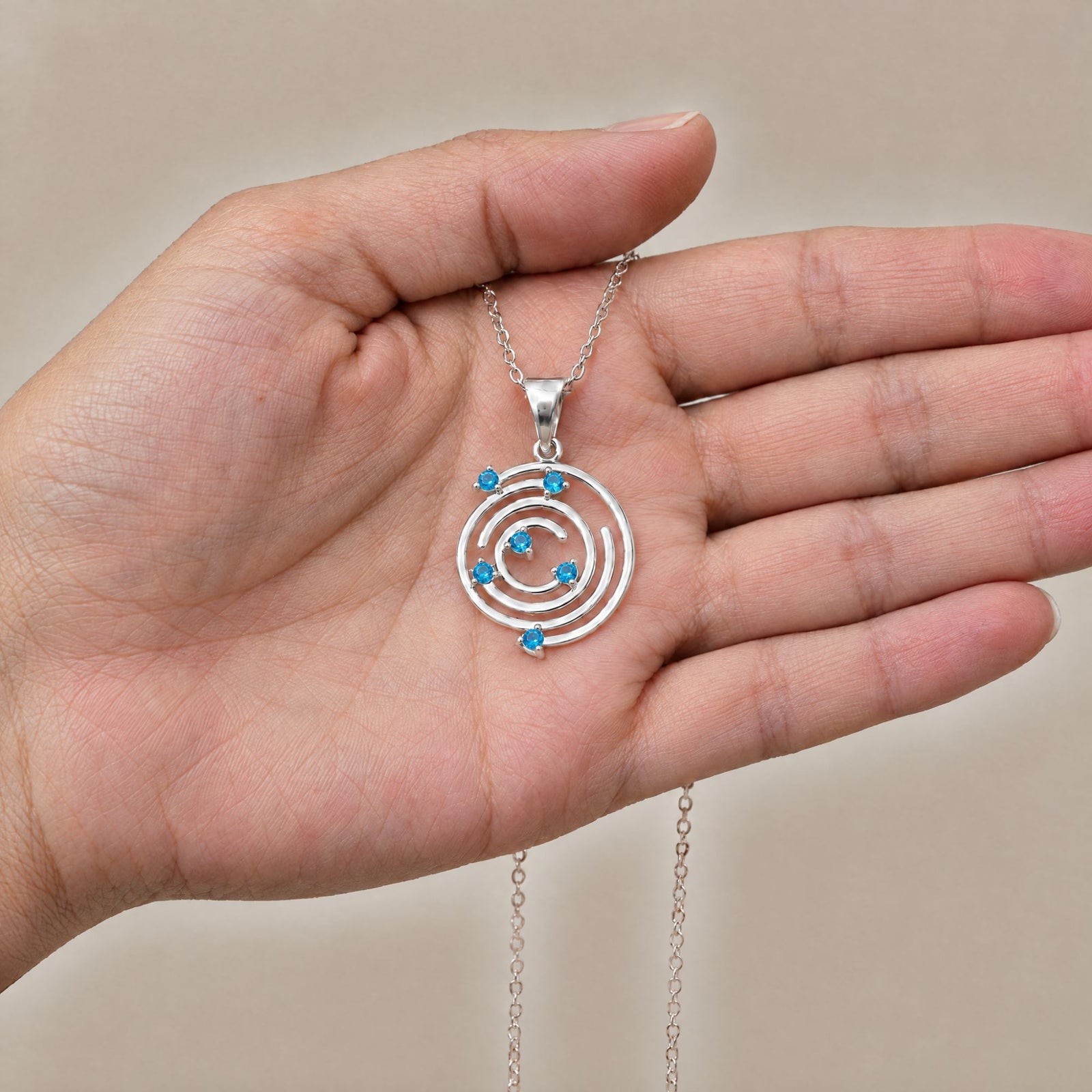 Collar Spiral de plata con piedra azul sobre una mano - Andrea Jewels