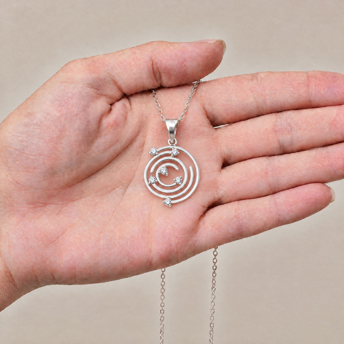 Collar Spiral de plata con piedra blanca sobre una mano - Andrea Jewels