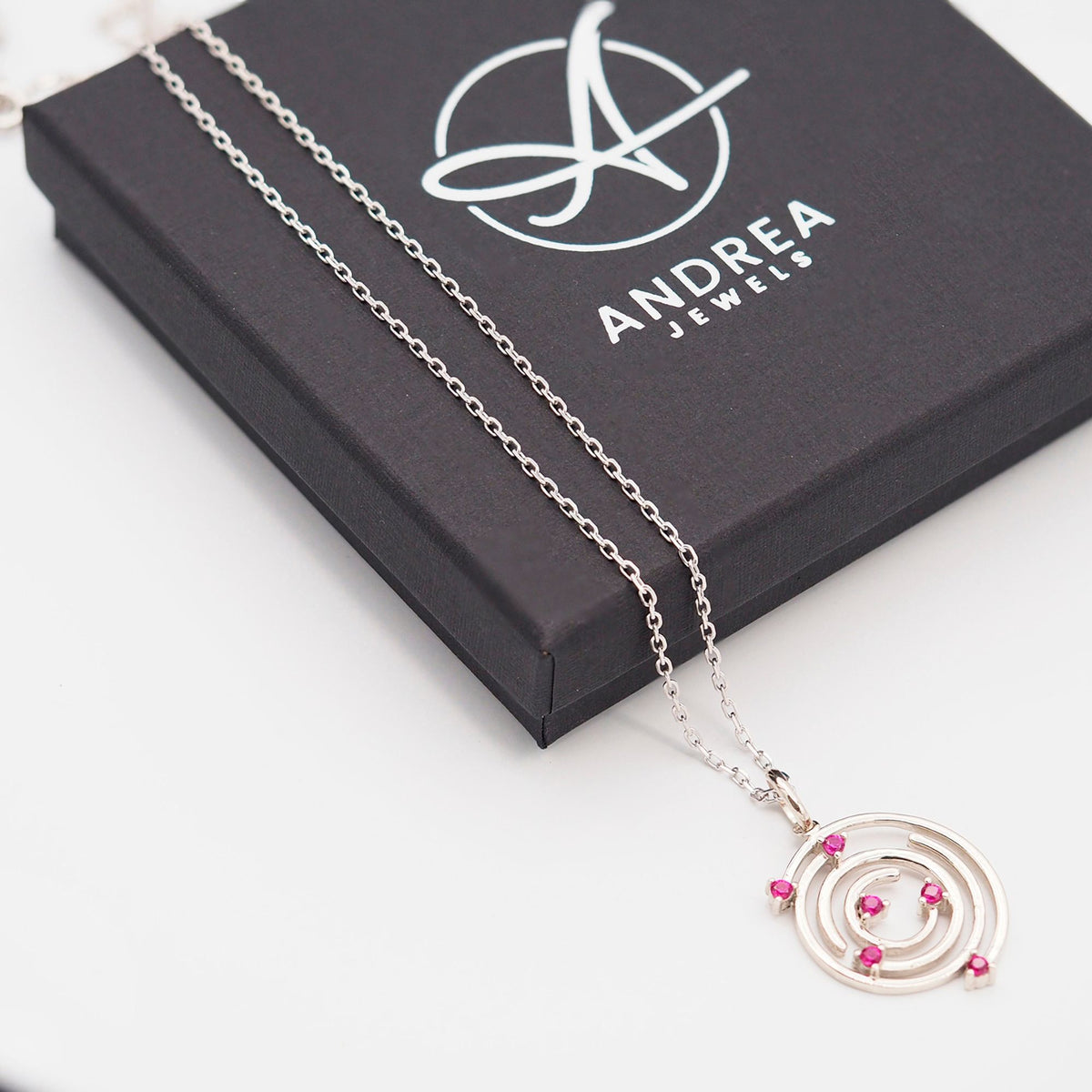 Collar Spiral de plata con piedra roja junto a su caja de regalo cerrada - Andrea Jewels