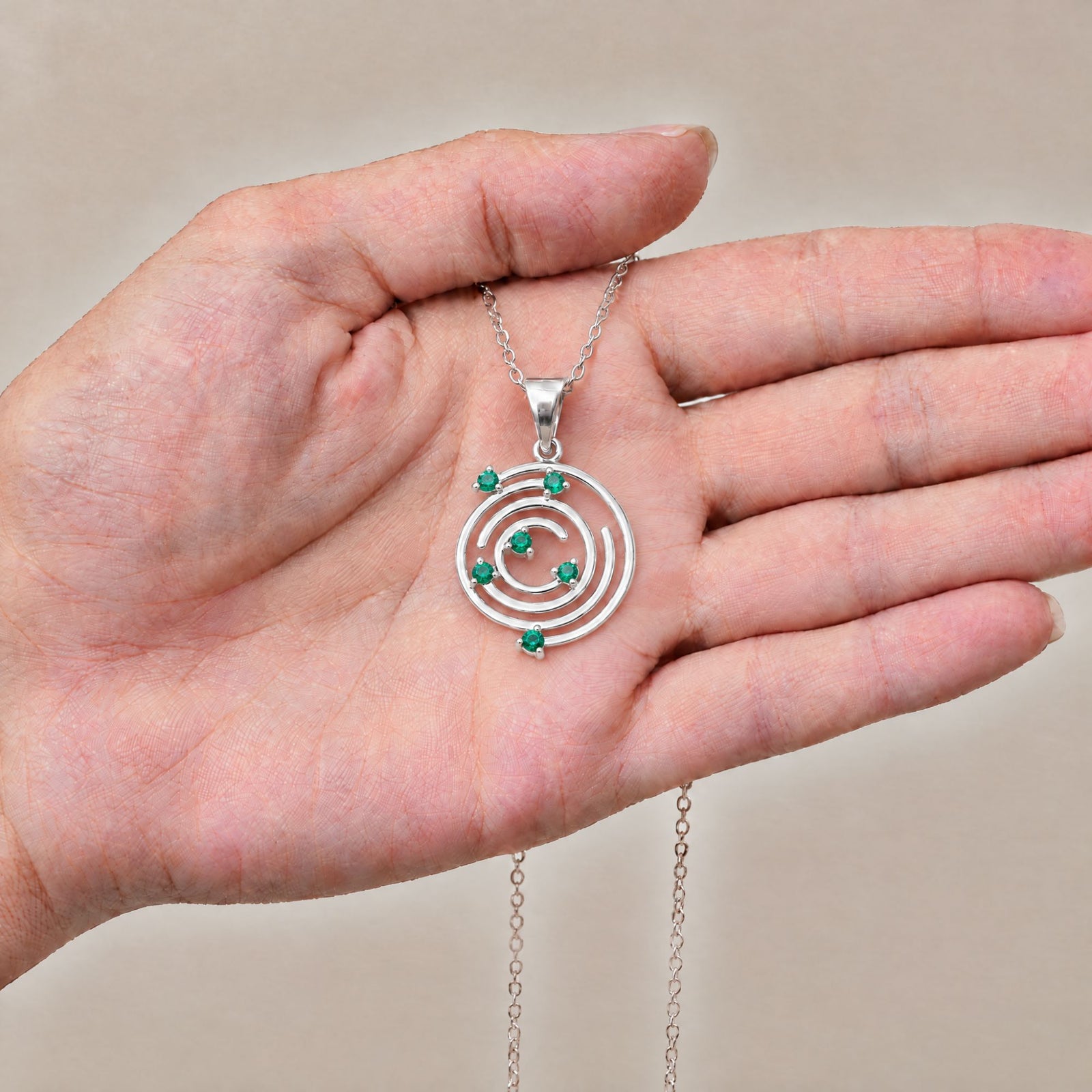 Collar Spiral de plata con piedra verde sobre una mano - Andrea Jewels