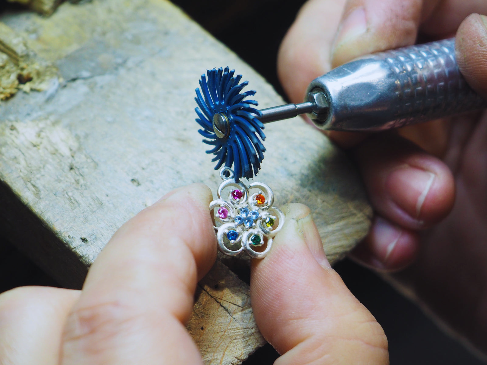 Pulido de un colgante de flor con piedras de colores en el taller de Andrea Jewels